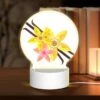 Round Acrylic Night Light, A Yellow Flower With A Pink Center Is Surrounded By Other Yellow Flowers.
