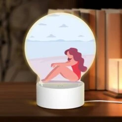 Round Acrylic Night Light, A Woman In A Red Bathing Suit Is Sitting On The Beach.