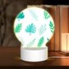 Round Acrylic Night Light, A Collection Of Green Leaves And Tree Branches.