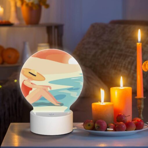 Round Acrylic Night Light, A Woman Wearing A Hat Sits On The Beach. -Acrylic Night Light Shop b620ee33517a59fb7a6c8ac7b3968786f26f7194
